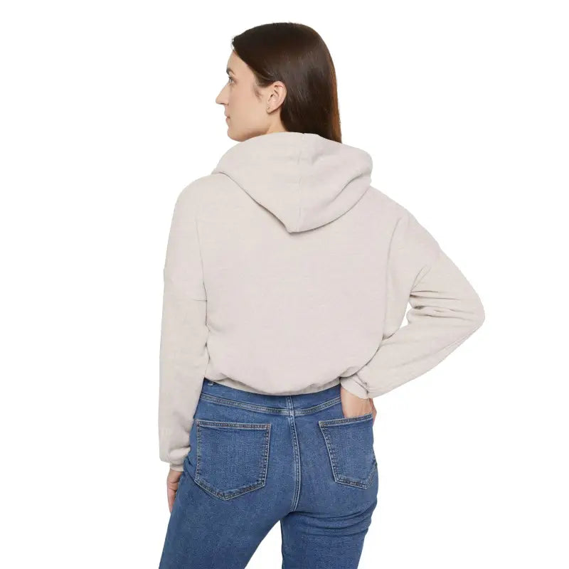 Woman in beige hoodie and blue jeans showcasing Coexist Women’s cinched bottom hoodie