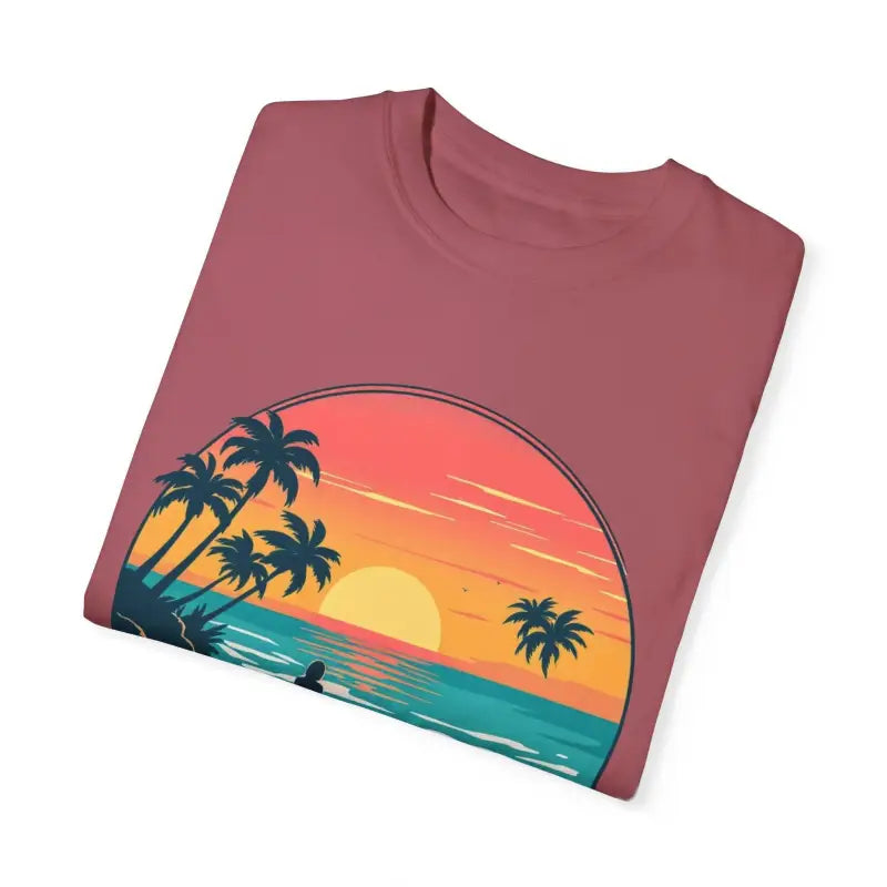 Folded maroon t-shirt featuring sunset beach graphic from Suns Out Buns Out collection
