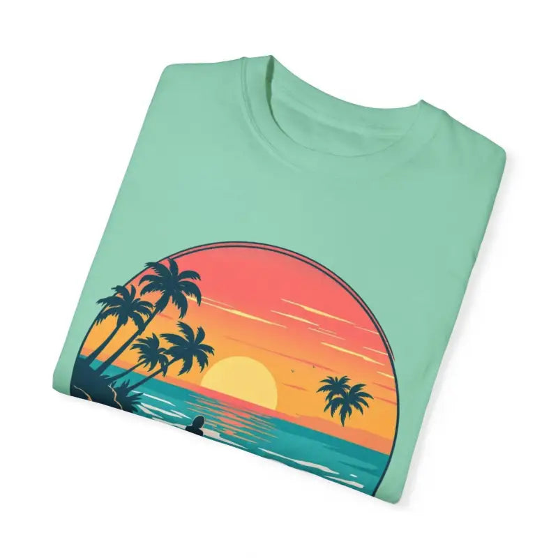 Folded mint-green t-shirt featuring sunset beach graphic from Suns Out Buns Out collection