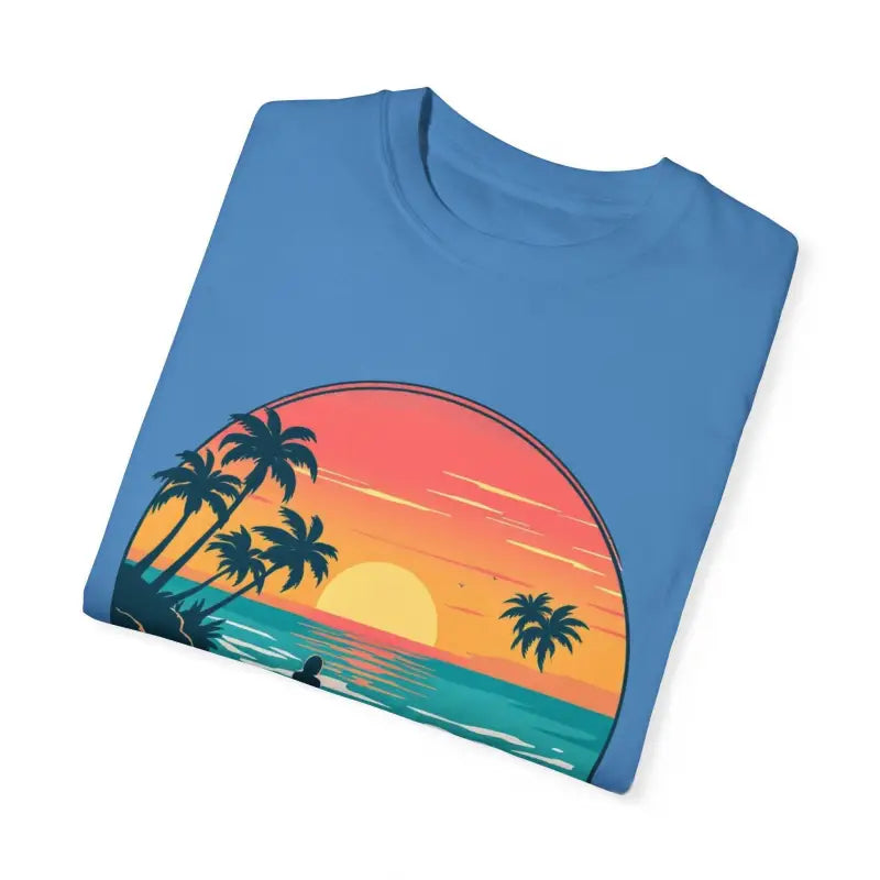 Folded blue t-shirt featuring beach sunset graphic for Suns Out Buns Out collection