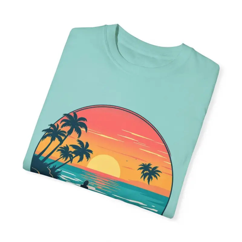 Folded light blue Suns Out Buns Out t-shirt featuring beach sunset graphic design