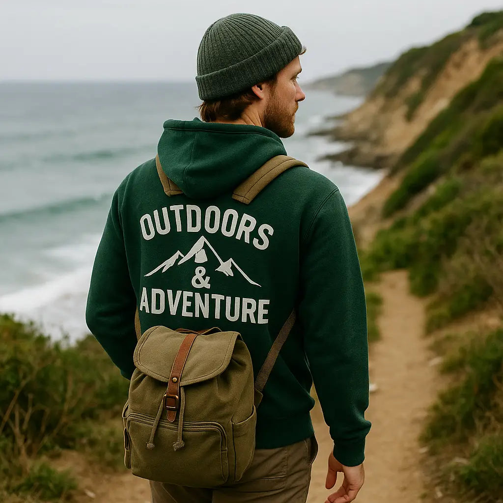 Person hiking a Rhode Island shoreline trail in a casual hoodie and backpack with ocean waves behind.