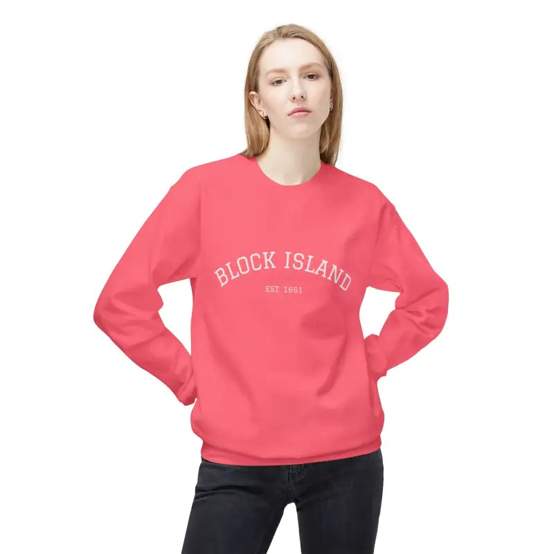 Woman wearing a long-sleeved pink Block Island EST 1661 sweatshirt and dark jeans