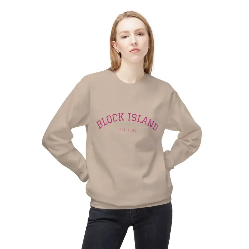 Woman wearing a light brown Block Island crewneck sweatshirt with pink lettering