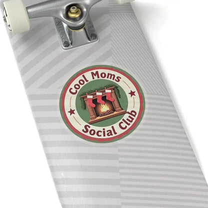 Circular Cool Moms Social Club sticker featuring a cozy fireplace and stockings