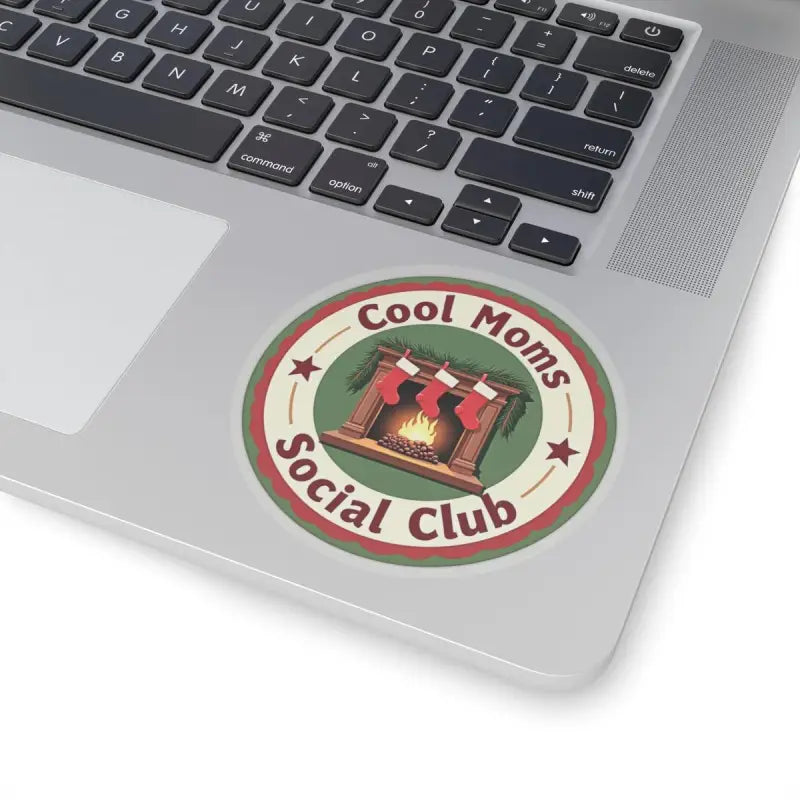 Circular Cool Moms Social Club sticker featuring a cozy fireplace and festive stockings