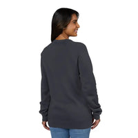 Woman wearing a dark gray crewneck sweatshirt with retro wave graphic and blue jeans