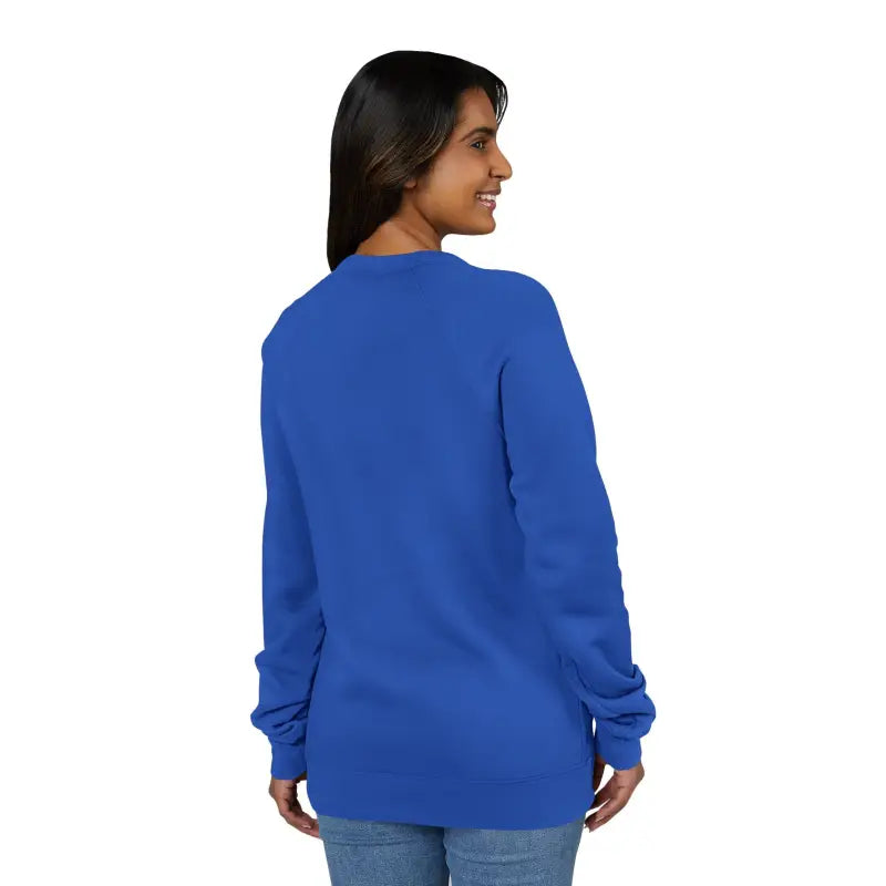 Woman wearing a long-sleeved blue crewneck shirt and blue jeans showcasing a dark gray retro wave graphic sweatshirt