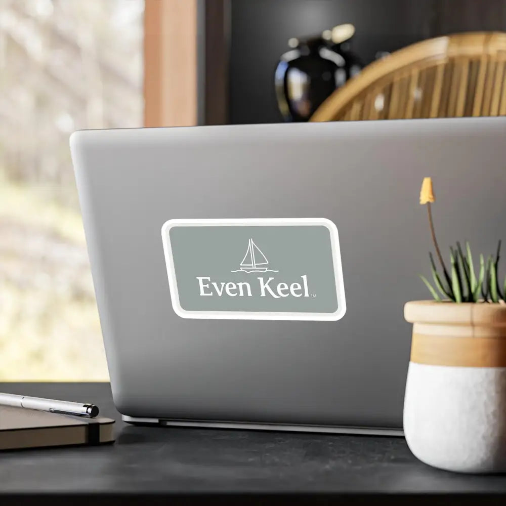 Laptop featuring sailboat sticker next to Gray Even Keel Sailboat Sign