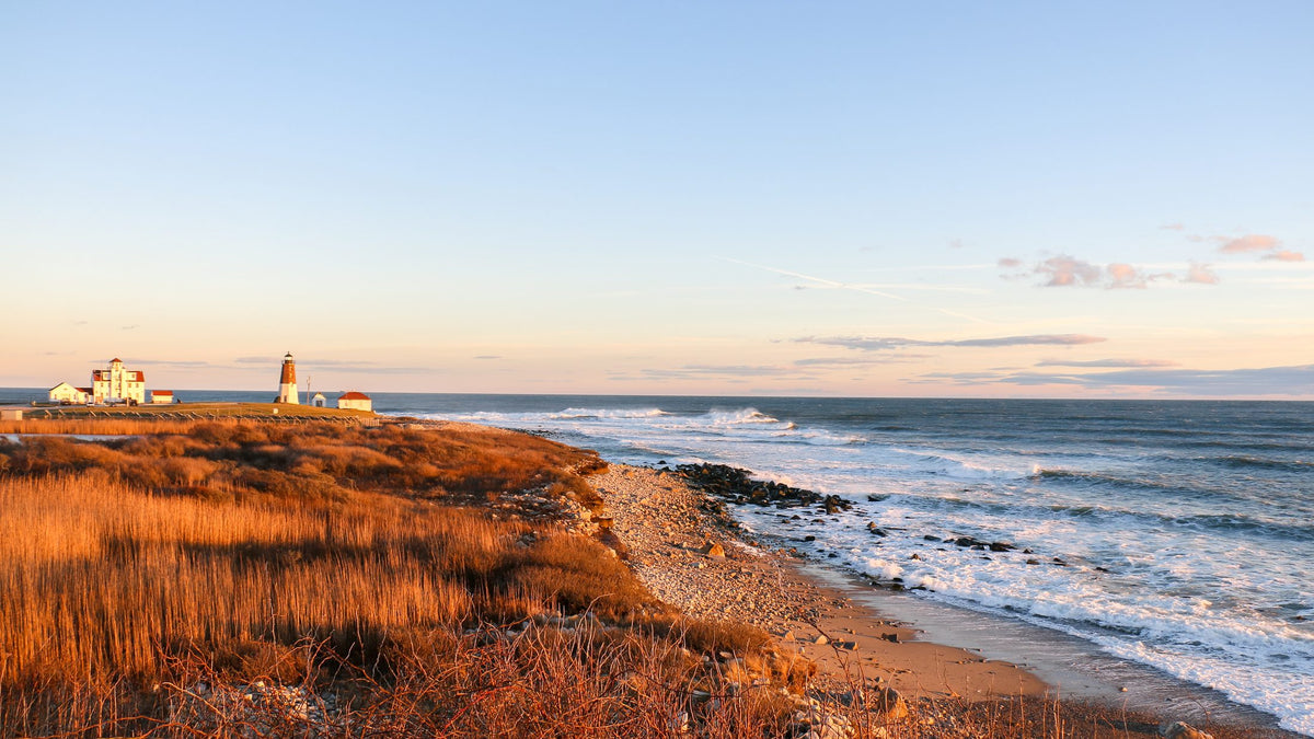 Point Judith Lighthouse and rocky Narragansett shoreline at golden hour.
